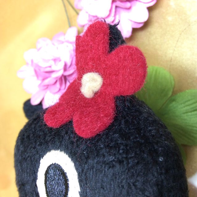 マタノアツコ先生お花のバッグを提げて赤いワンピースを着る黒猫メメちゃん縫いぐるみの頭の花の部分アップ写真