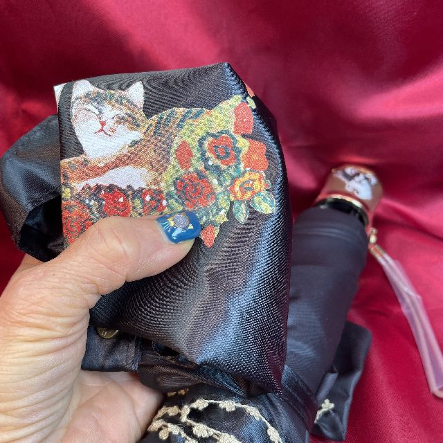 猫のマンハッタナーズ折りたたみ傘とバッグのセット天使の祝福柄のバッグを折り畳んで手で持った画像