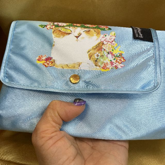 マンハッタナーズのレインバッグ「ミケちゃんの花冠」柄のブルー色を手に持った画像