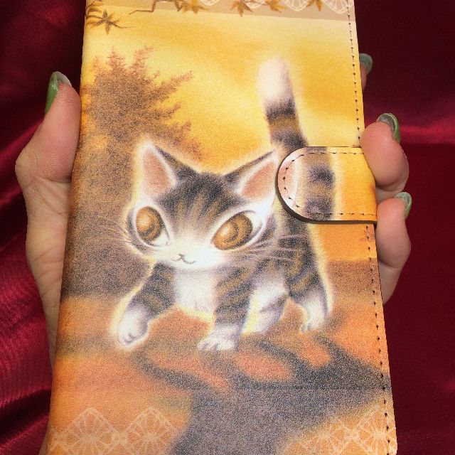 猫のダヤンのブック型スマホケース「光の中」柄を手に待った画像