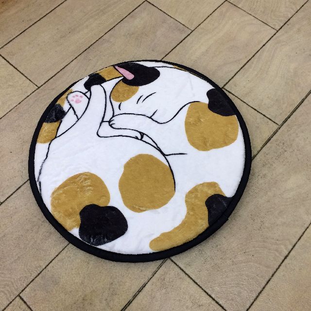 大西賢の丸い三毛猫チェアパッドを床に置いた画像