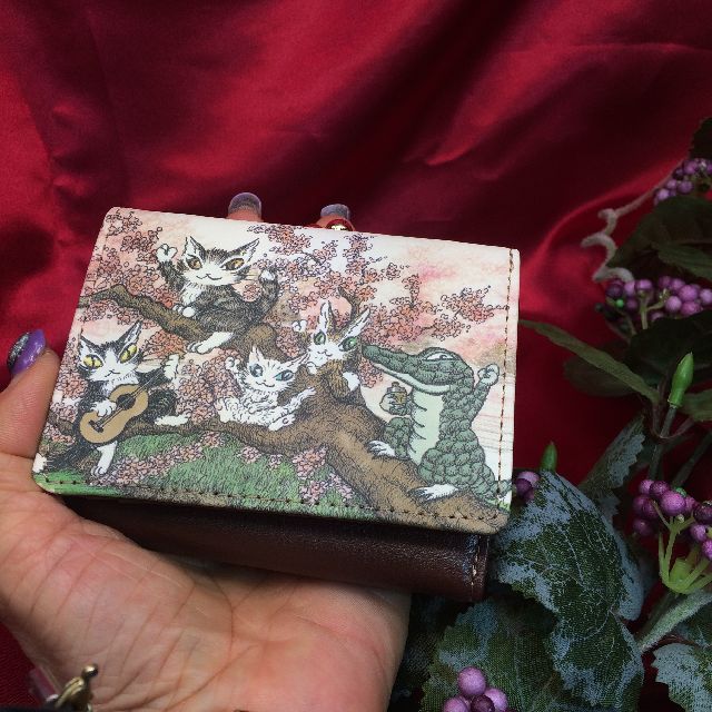 猫のダヤンのがま口三つ折り財布「永遠の桜」柄を掌に載せた画像