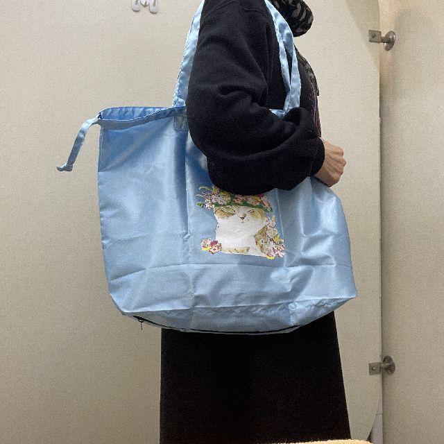 マンハッタナーズのレインバッグ「ミケちゃんの花冠」柄のブルー色を肩に掛けた画像
