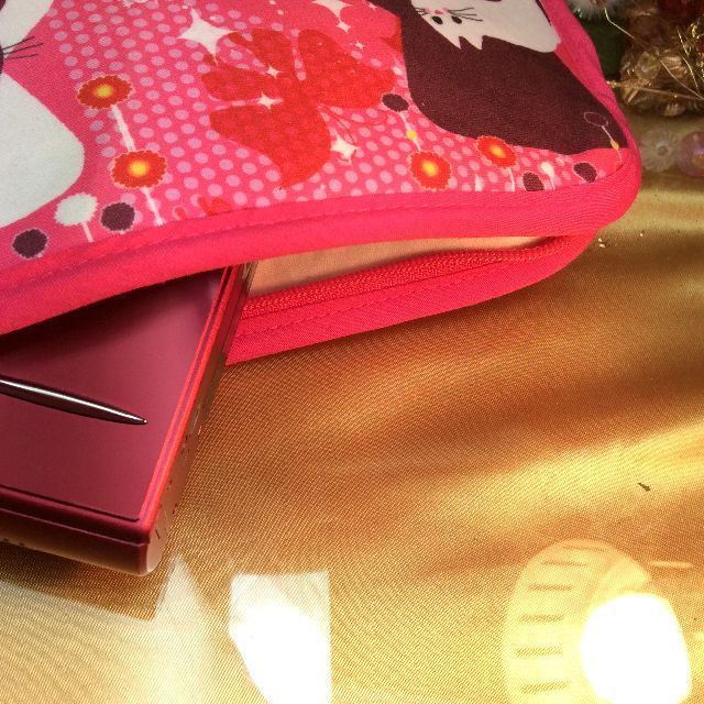 猫柄スマホポーチのファスナーを開いて、携帯電話を入れてみた画像