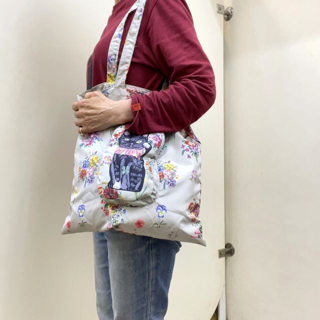 エイトミリオンワークスのナタリーレテのエコバッグラッキーキャットを肩に掛けた画像